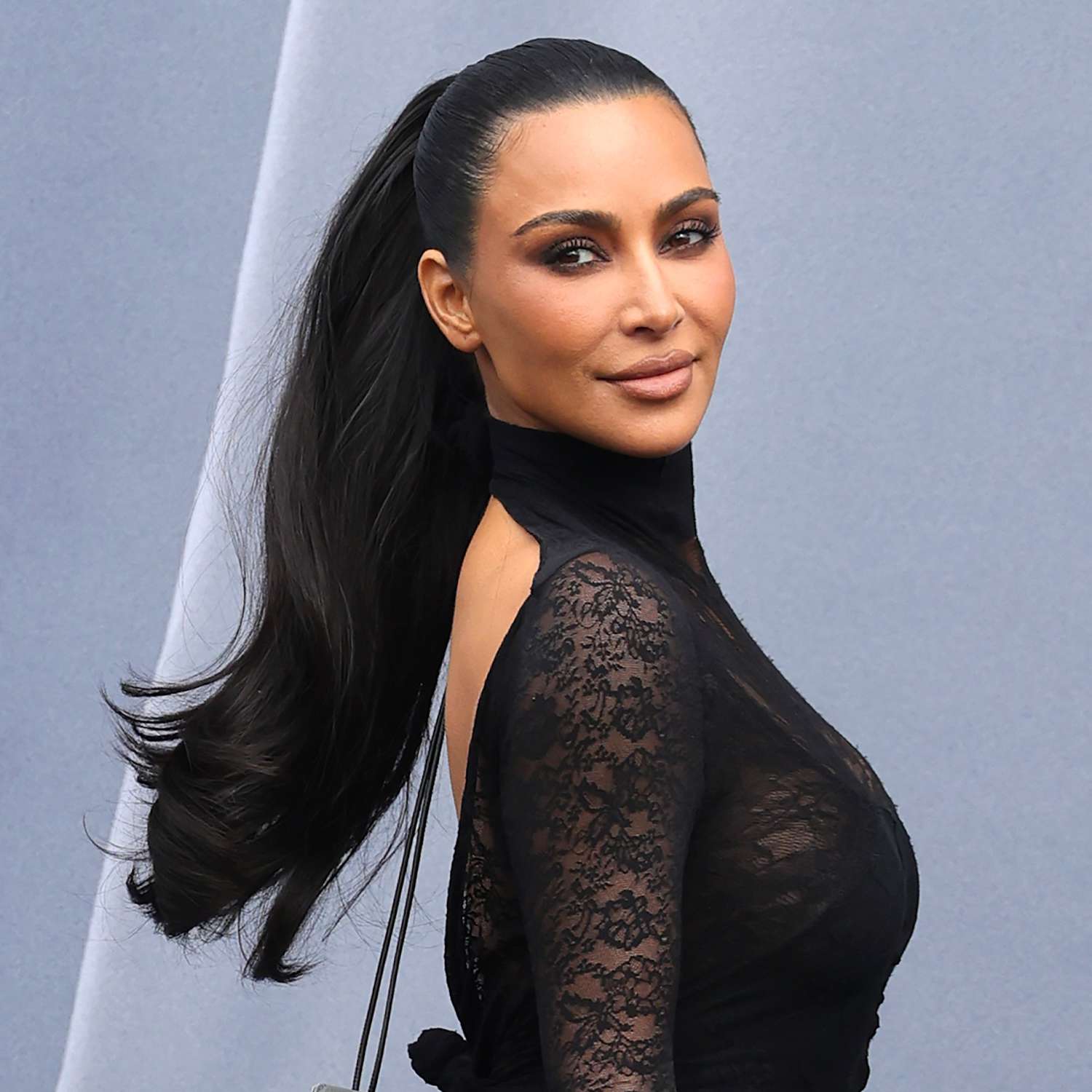 Kim Kardashian attends Paris Fashion Week in a thick and flirty mid-height ponytail against an open back top