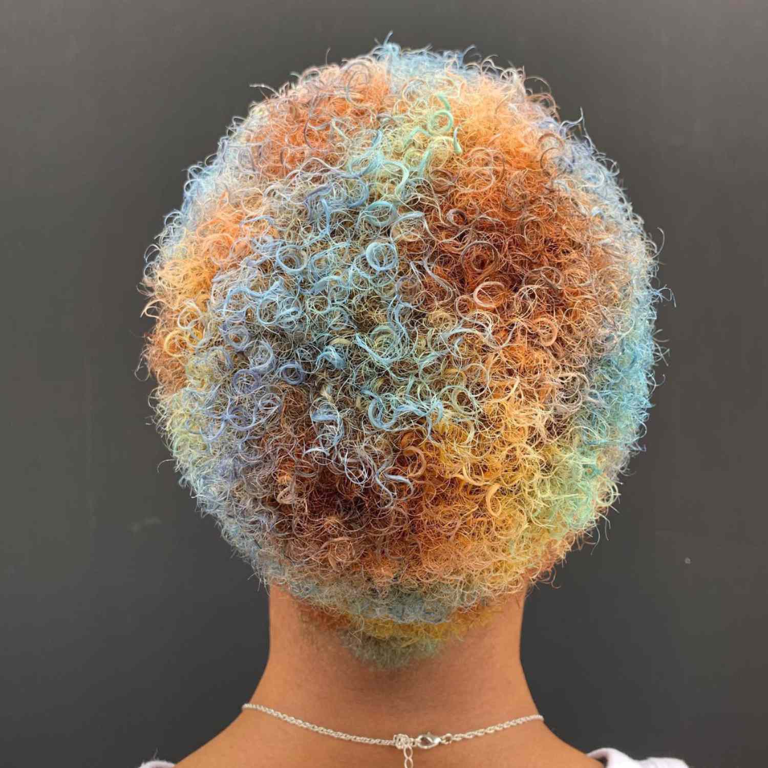 Curly afro hair with blue yellow and orange dye.