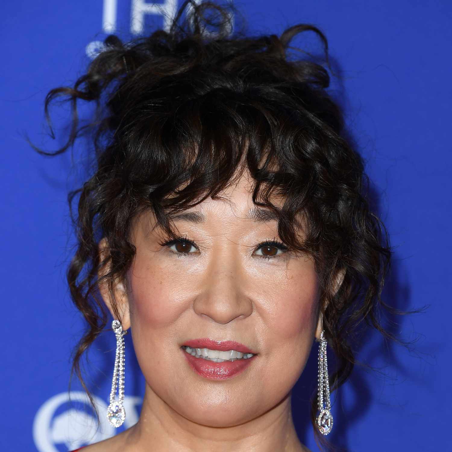 Sandra Oh wears wavy french bangs with a wavy textured updo to a Film Festival