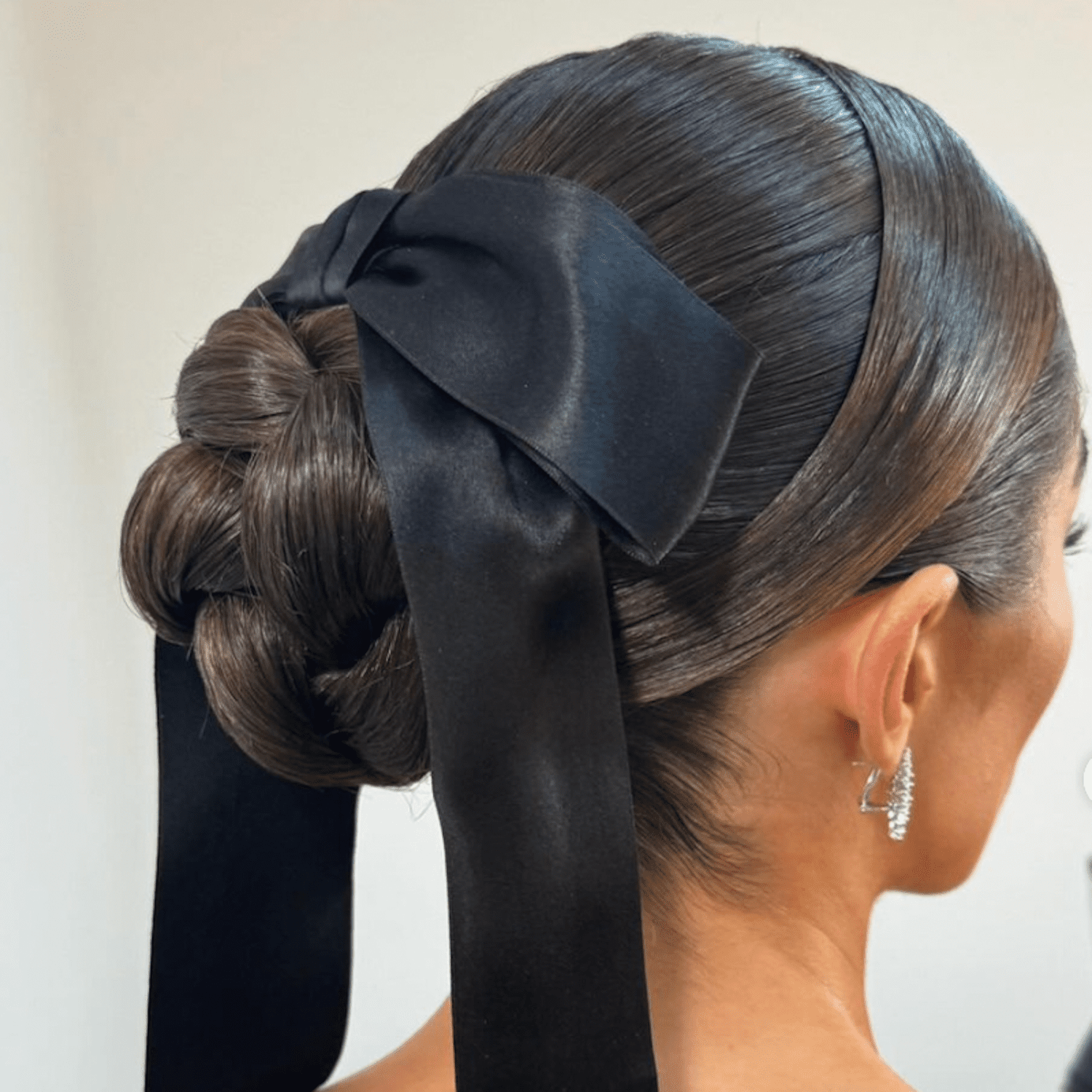 Olivia Culpo wears a braided chignon with a black stain ribbon in her espresso brunette hair