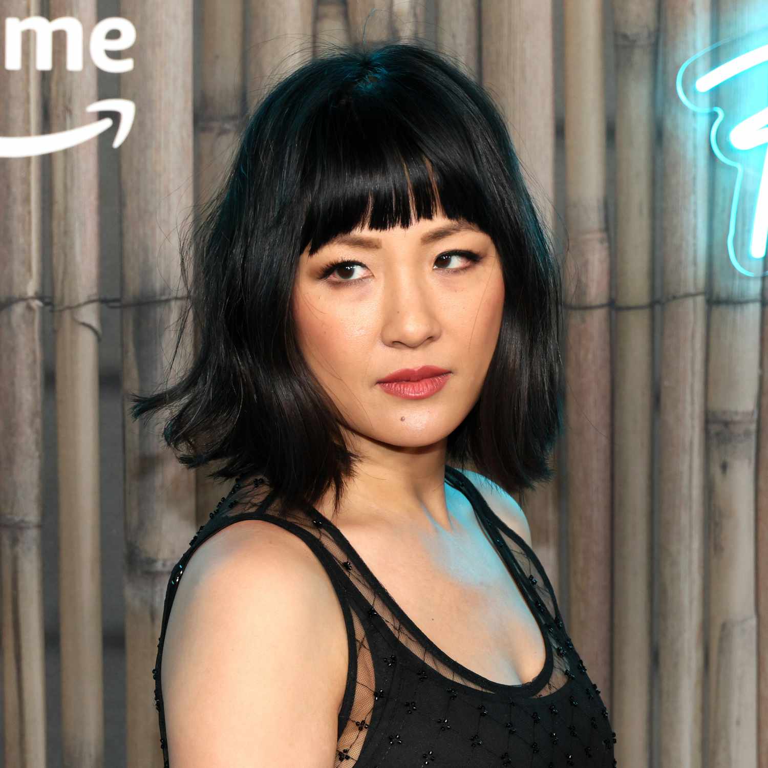 Constance Wu with jet black shoulder length hair and bangs