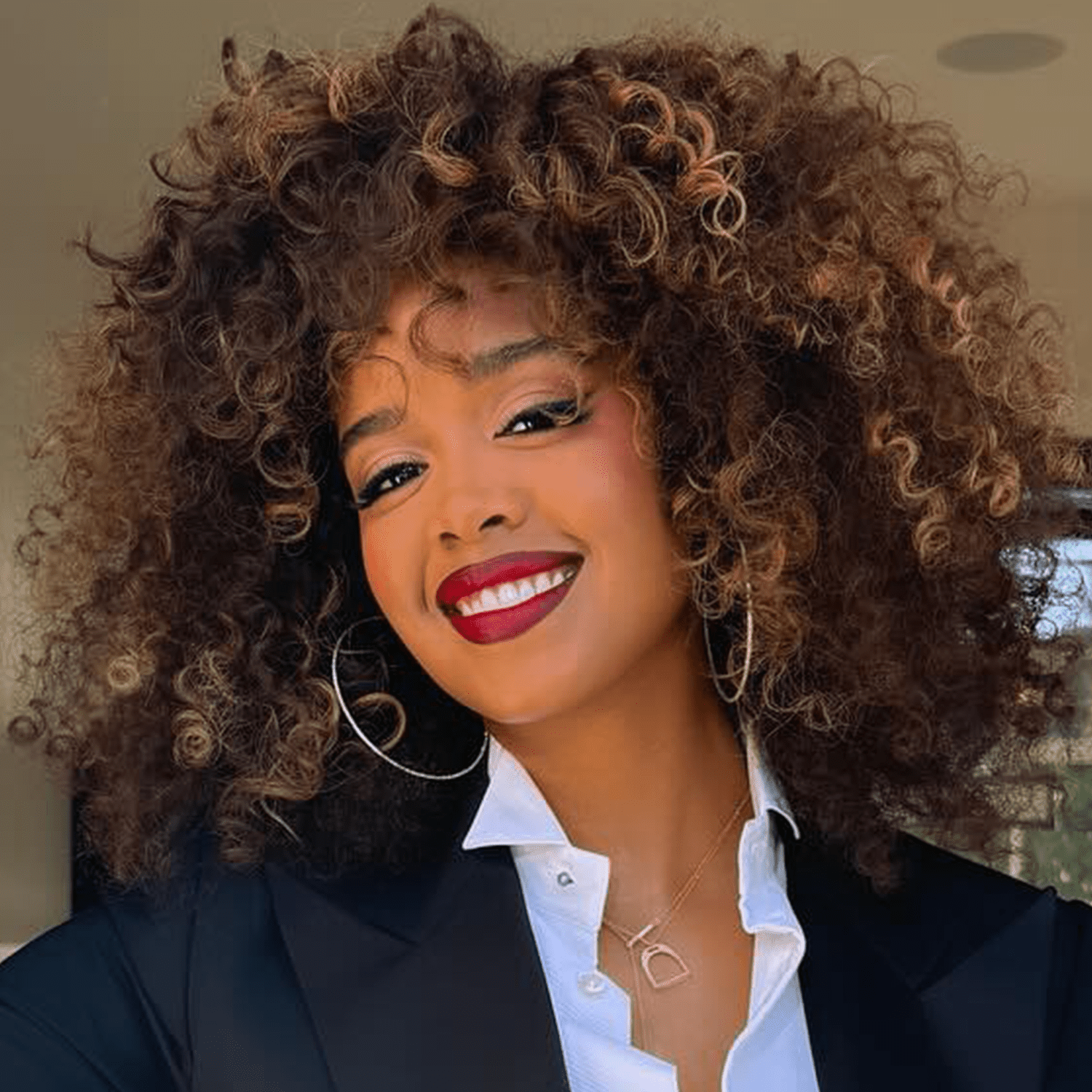 H.E.R with dark brown curls and caramel highlights 