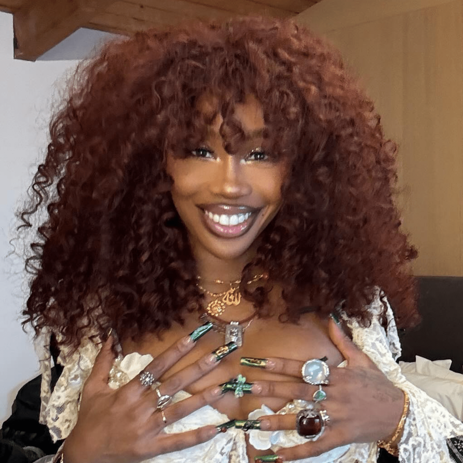 SZA with cherry cola-colored curly hair with curly bangs.