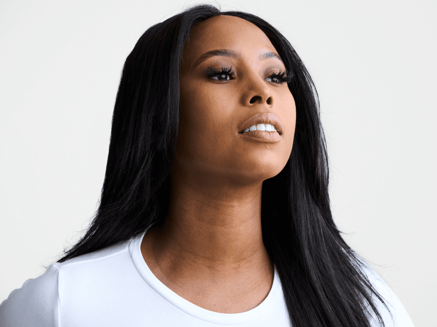 A Black woman wearing a white T-shirt with straight relaxed hair.