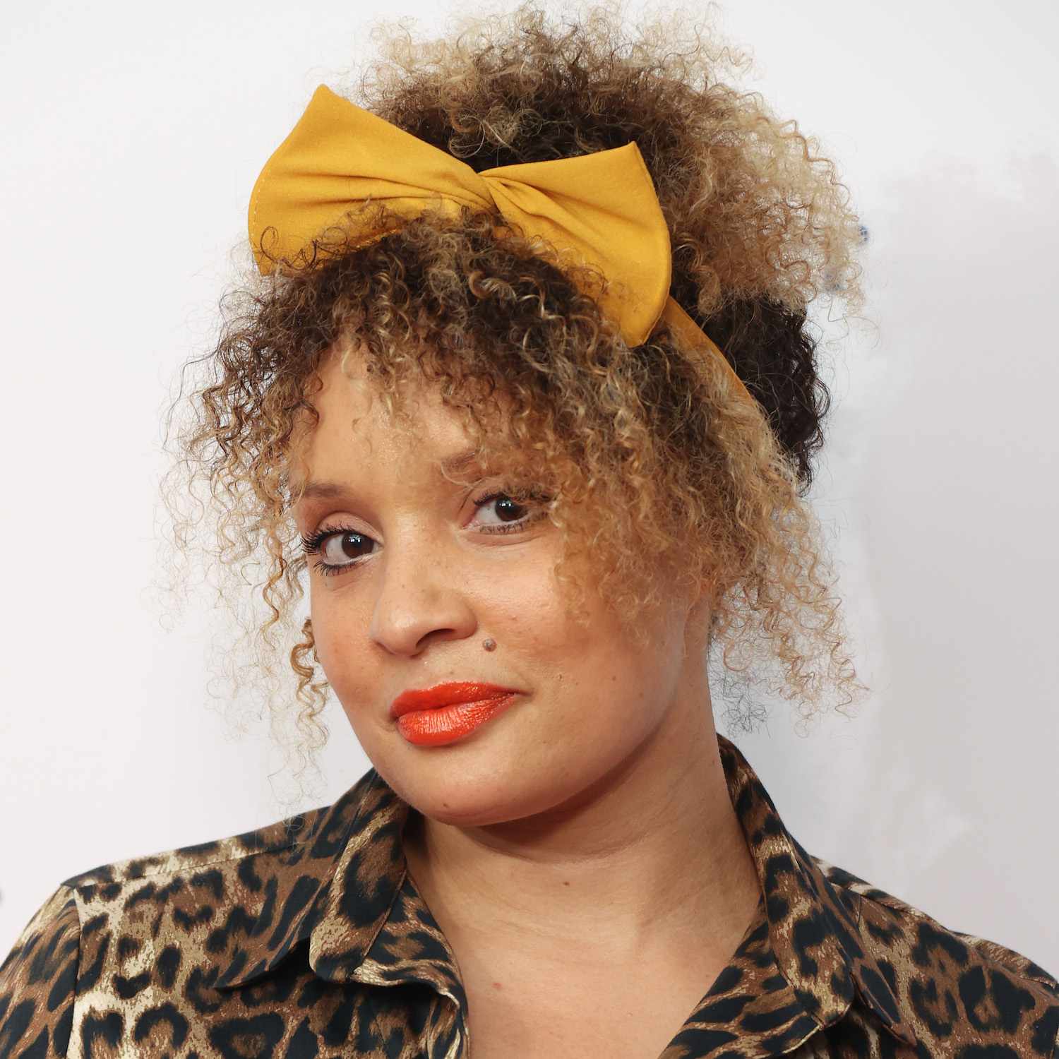 A woman with her textured hair tied up with a yellow ribbon